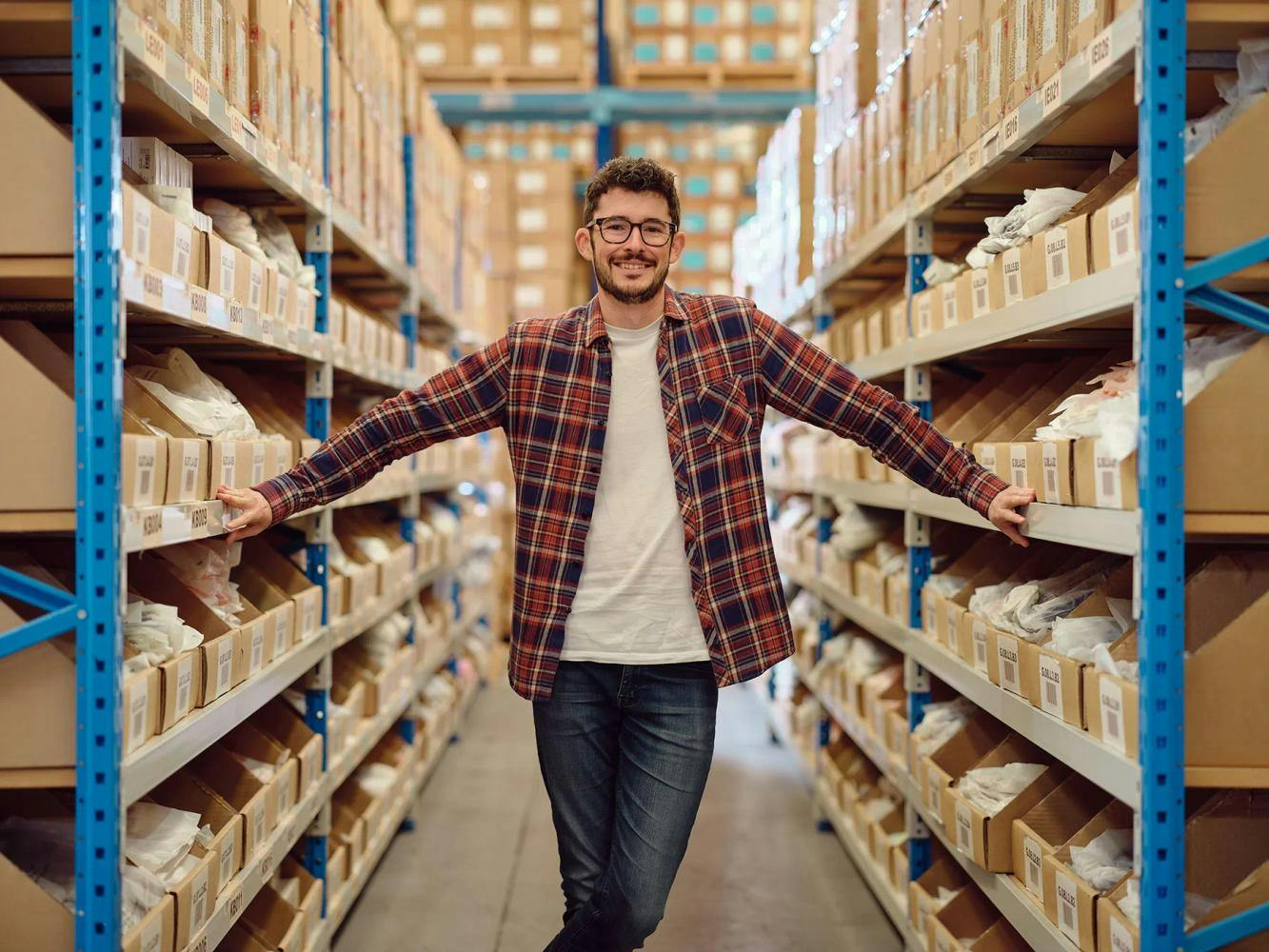 Man standing warehouse with hands on shelves
