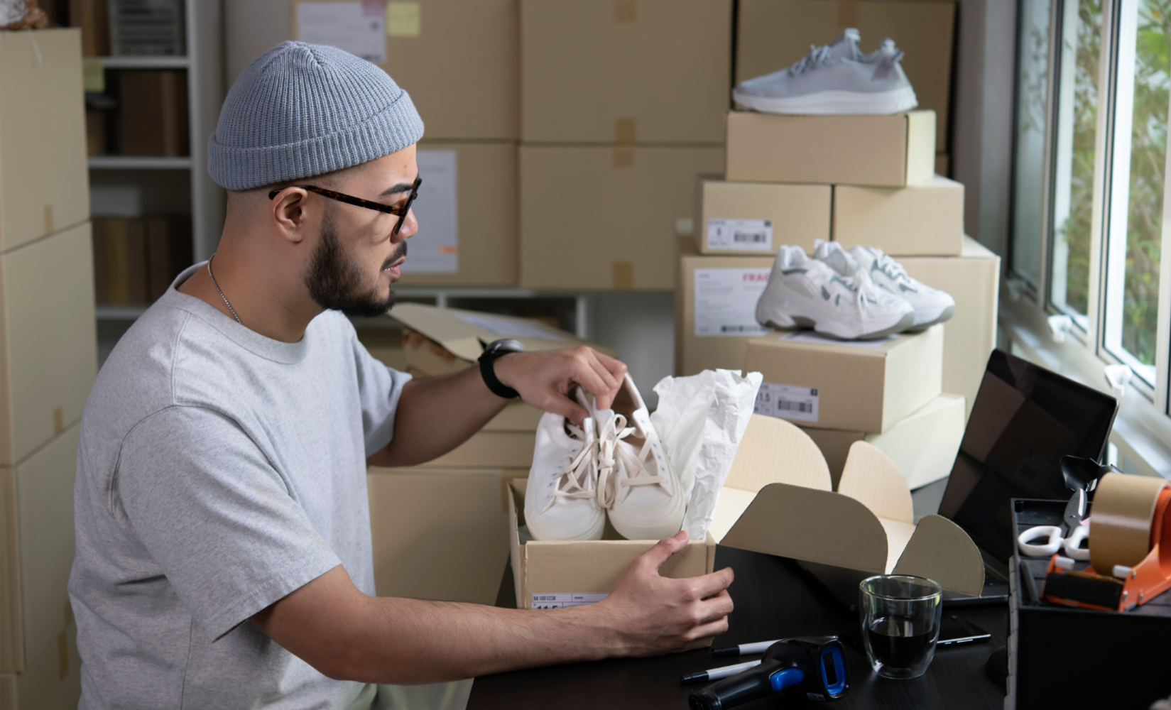 Man wearing beanie packs shoes into shoe boxes (multi-brand strategy)