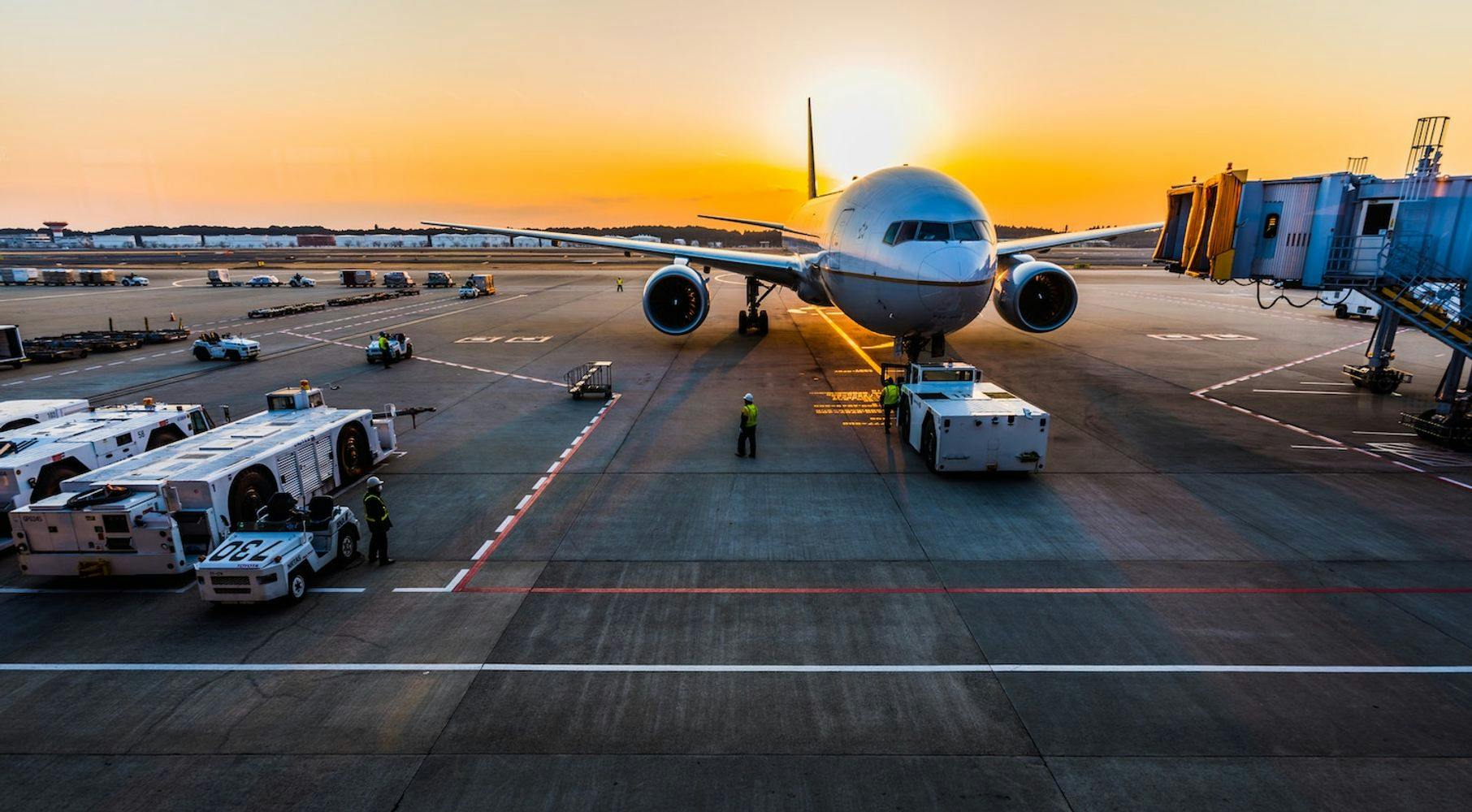 plane at airport with vehicles spaced around at sunset