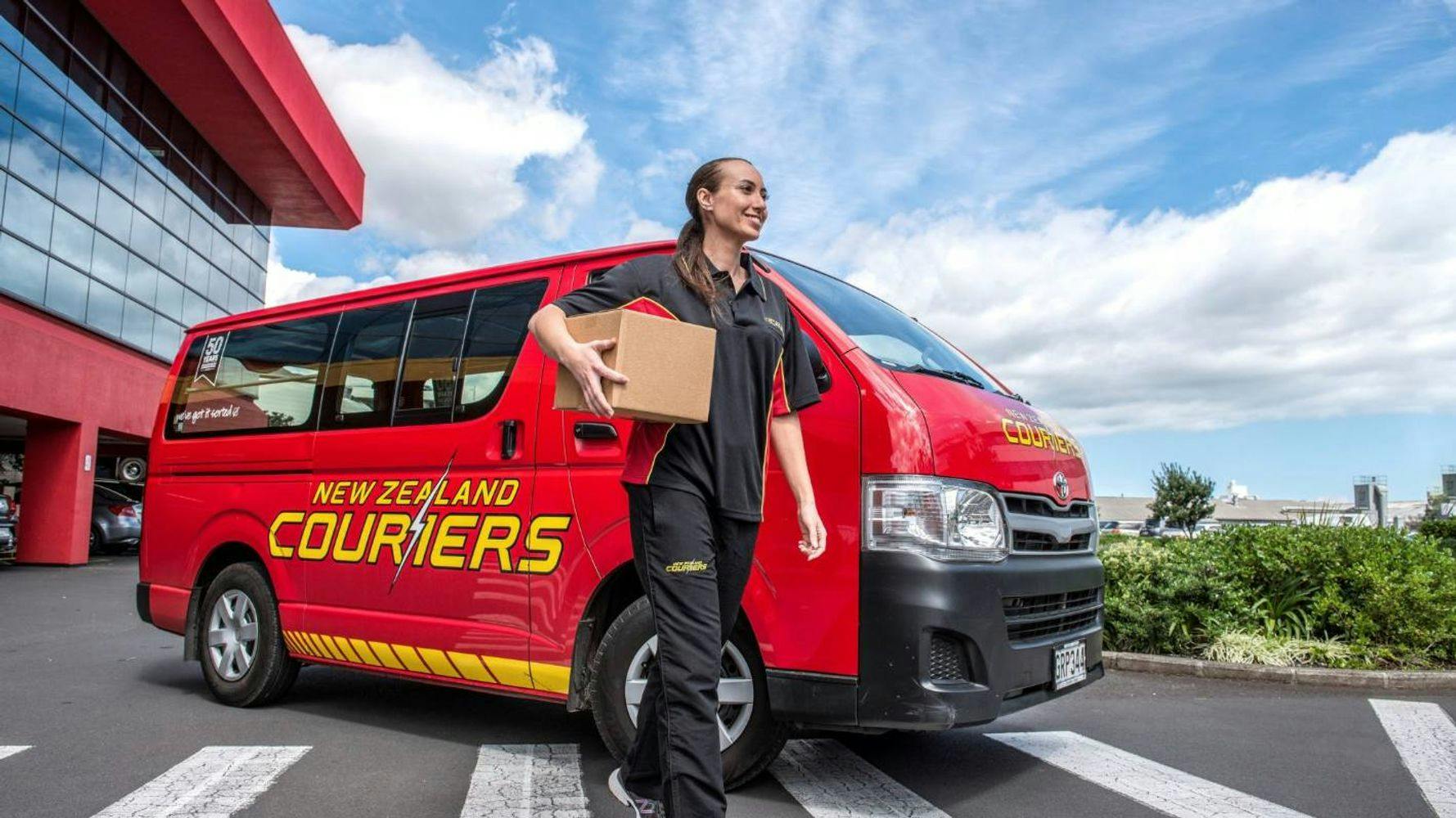 Women holding package in front of NZ Couriers Van