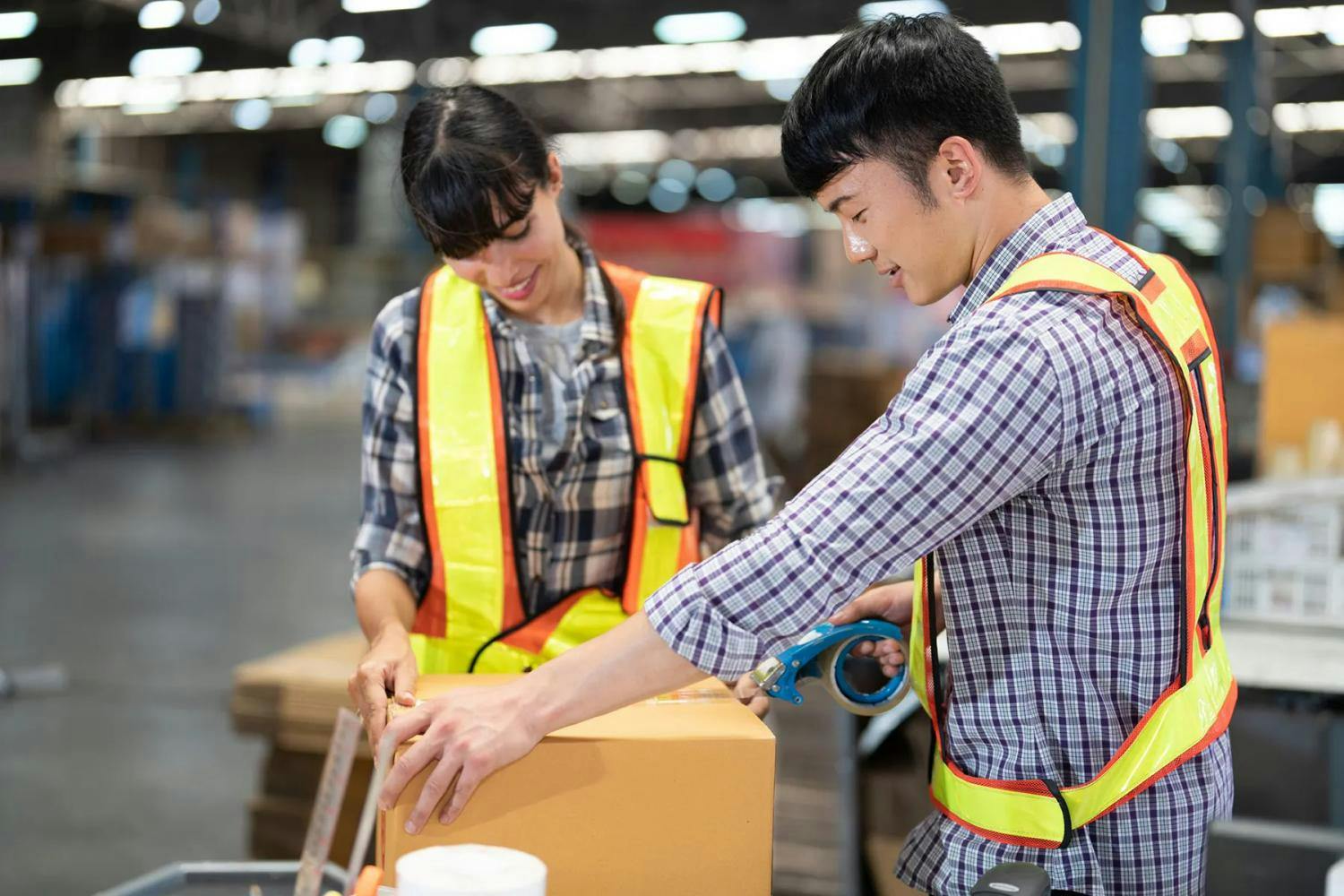 Two warehouse workers packing boxes in a large storage depot