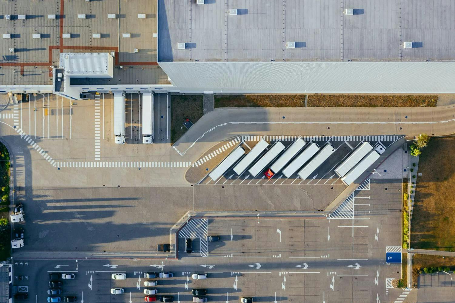 Drone photo of trucks with shipping containers parked outside a warehouse